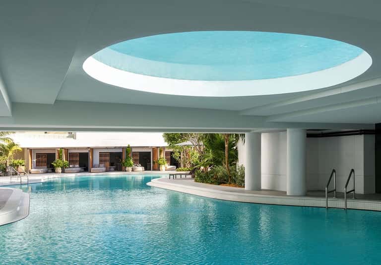 Indoor swimming pool with circular skylight ceiling and covered lounging area