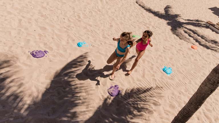 Two children playing with colorful discs on sunny beach