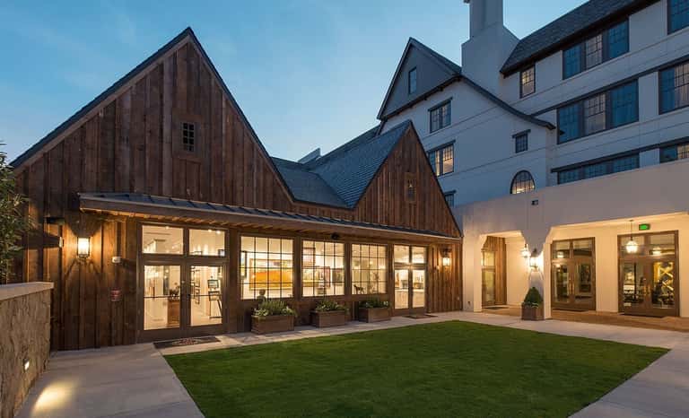 Dark wood barn-style buildings with large windows and courtyard at twilight