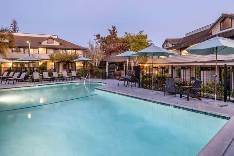 Resort swimming pools with lounge chairs and green umbrellas at dusk