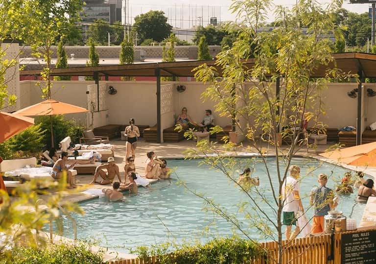 Overhead view of busy resort pool with multiple swimmers and guests relaxing by water