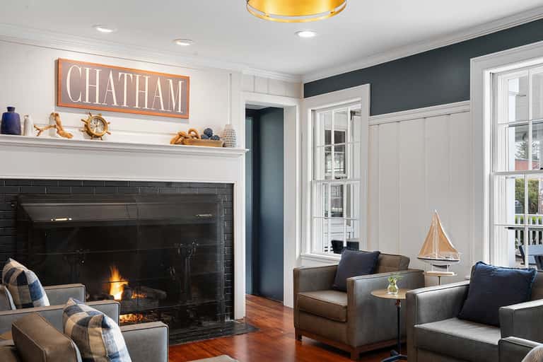 Fireplace lounge with dark tile surround, sailboat decor, and nautical-themed mantel