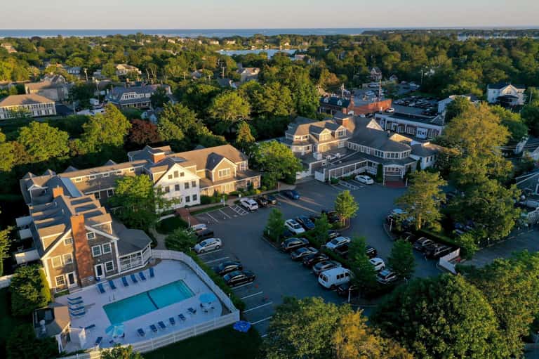 Aerial view of residential community with pools, parking areas, and tree-lined streets