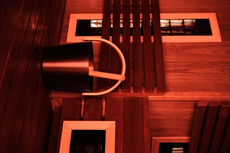 Overhead view of red wooden spa interior with neon orange accents, curved architectural elements, and skylight