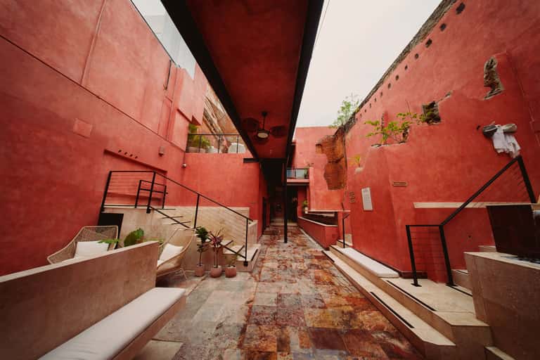 Red-painted covered walkway with stairs, benches, and potted plants