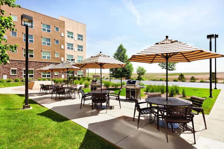 Outdoor patio with striped umbrellas, dining tables, and pastoral landscape views