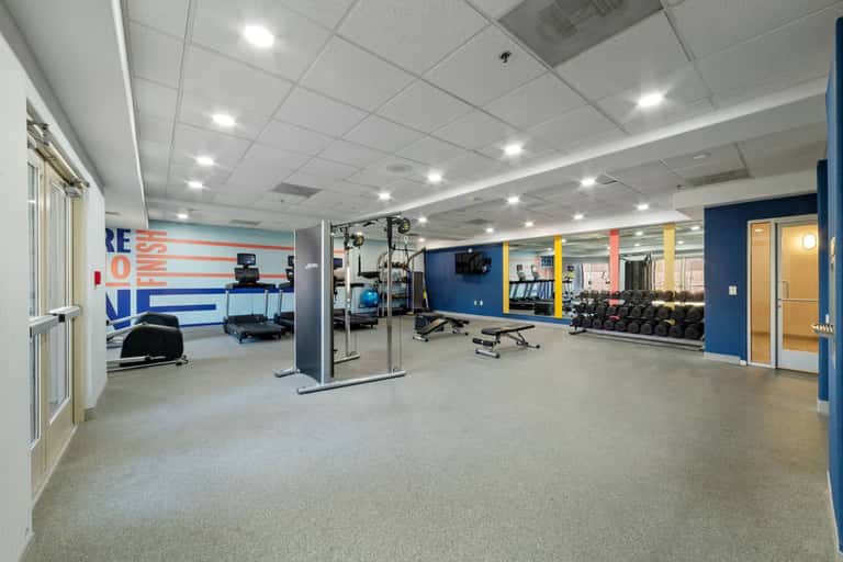 Spacious fitness facility with workout equipment, blue walls, and motivational wall art