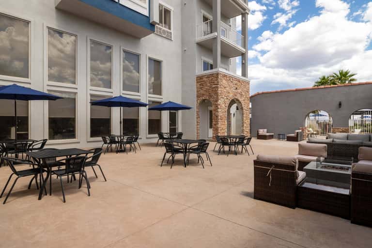 Outdoor courtyard with dining tables, blue umbrellas, and stone architectural features