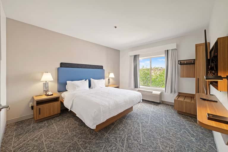 Hotel bedroom with blue headboard, wood furnishings, and scenic window view