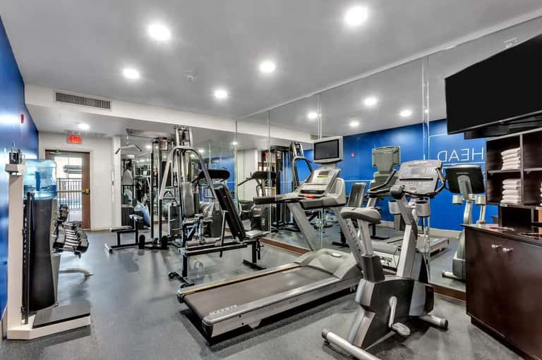 Well-equipped fitness center with cardio machines, weight equipment, blue accent walls, and mirrored walls