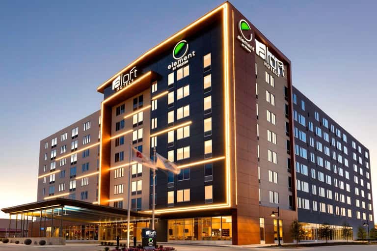 Modern hotel exterior at night with illuminated gold signage and multi-story facade