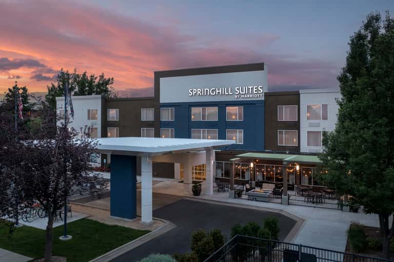 SpringHill Suites by Marriott exterior at dusk with modern architecture, illuminated signage, and covered patio seating.