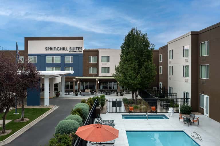 Aerial view of Springhill Suites hotel complex with two pools, orange umbrellas, and surrounding buildings
