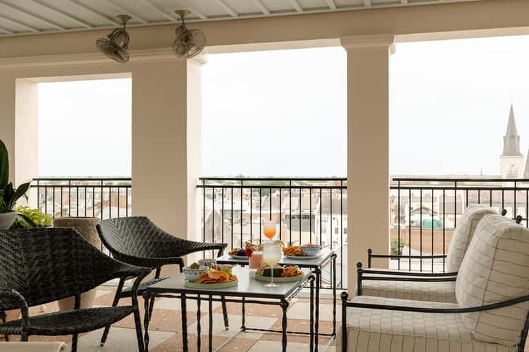 Covered rooftop lounge with contemporary furniture, panoramic city views, and ceiling fans
