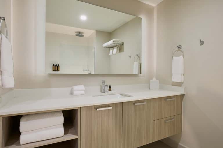 Clean bathroom with double vanity, large mirror, and white marble countertop