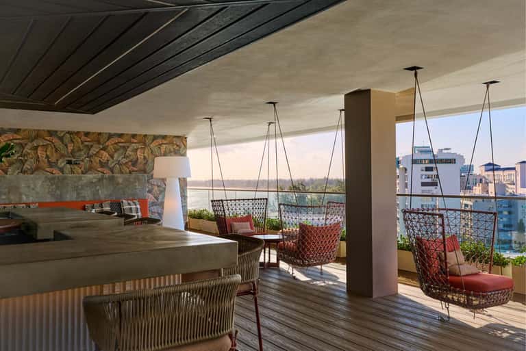 Rooftop terrace lounge with hanging chairs, fireplace, and waterfront views