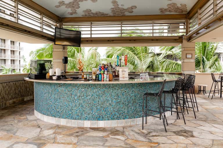Curved turquoise tile bar counter with palm trees visible through open windows