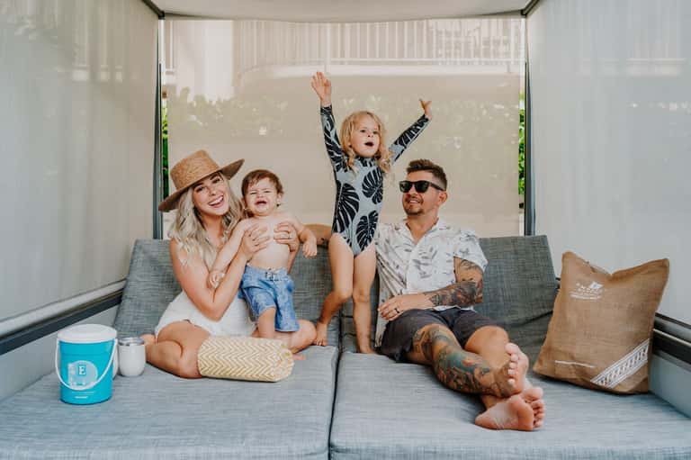 Family of four relaxing on gray couch in modern screened outdoor living space
