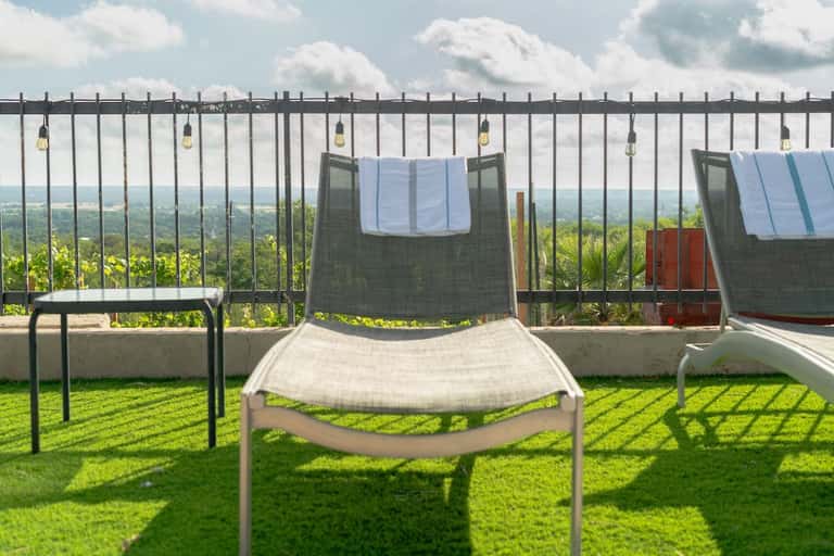 Lounge chair with towel on hillside terrace overlooking vast green landscape with railing