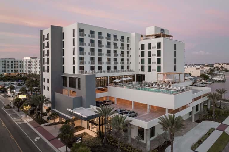 Modern beachfront hotel building with pool deck, palm trees, and architectural rendering