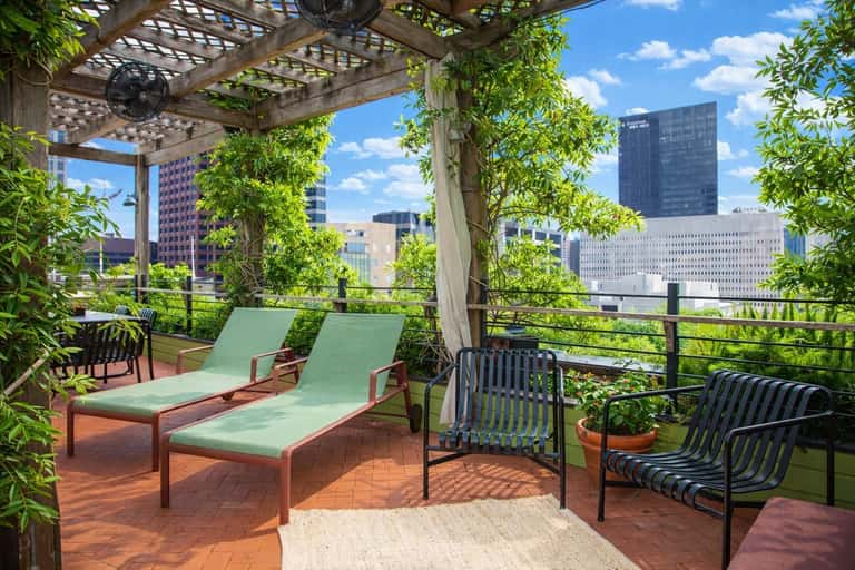 Rooftop terrace with lounge chairs, pergola, and city skyline views