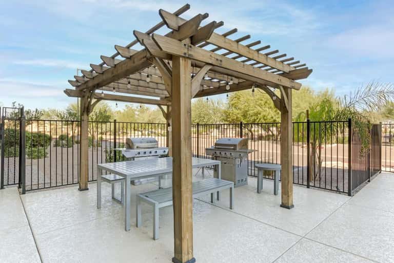 Outdoor grilling area with wooden pergola, multiple BBQ stations, and resort landscaping