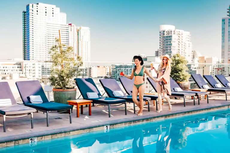 Rooftop pool deck with lounge chairs overlooking urban skyline and high-rise buildings