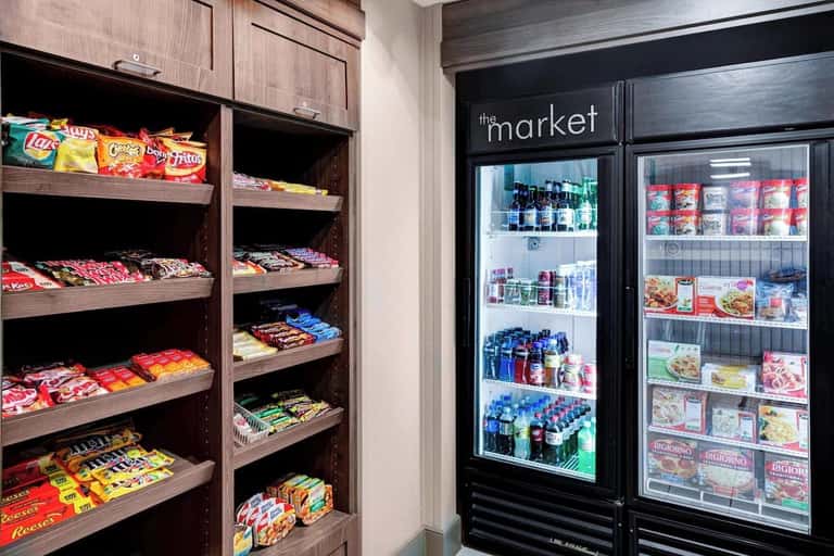 Hotel market convenience area with wooden snack shelves and refrigerated beverage and food display cases