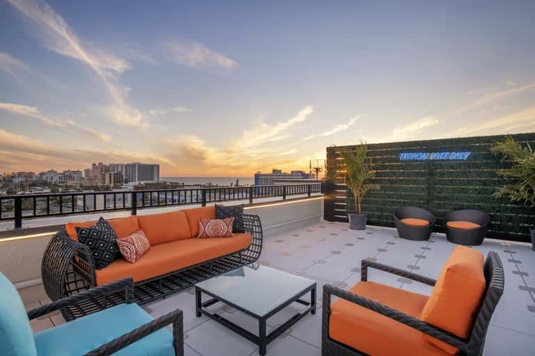 Rooftop lounge at golden hour with orange seating, water feature, and city views