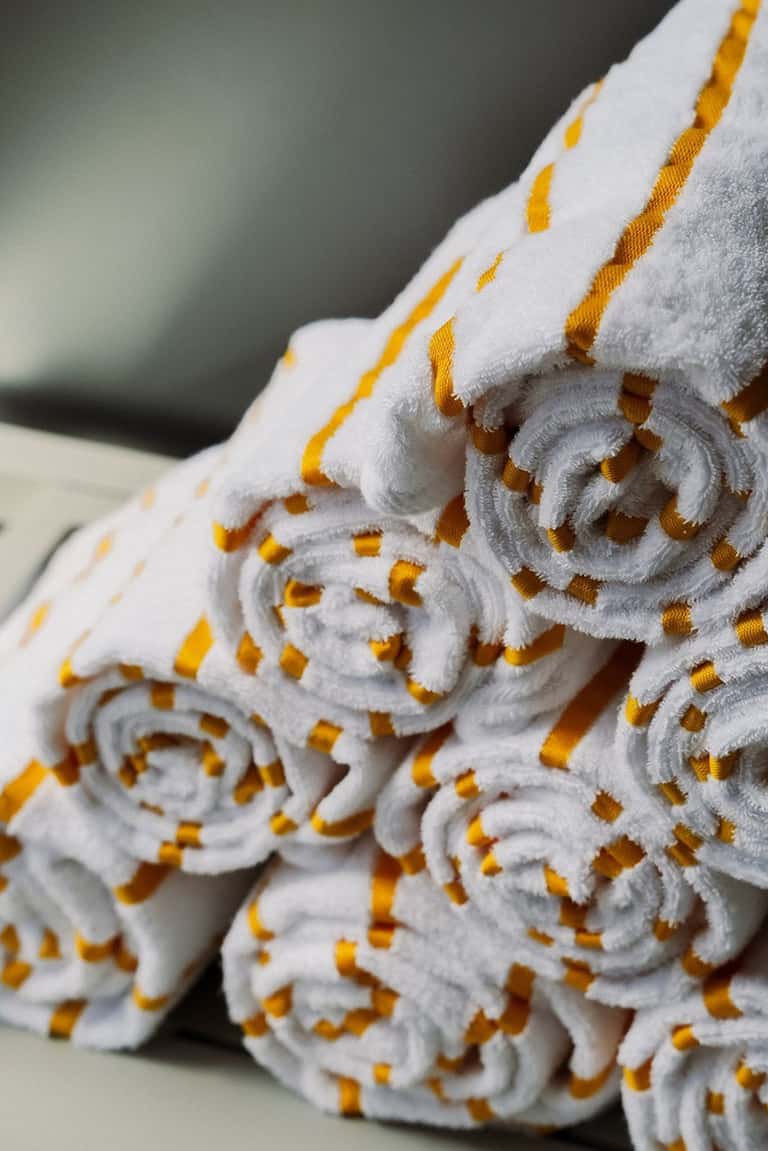 Rolled white towels with gold stripe detail stacked at resort spa