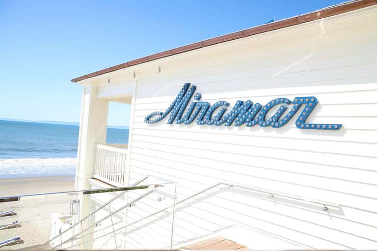 Beachfront pavilion with blue marquee signage overlooking sandy beach and ocean