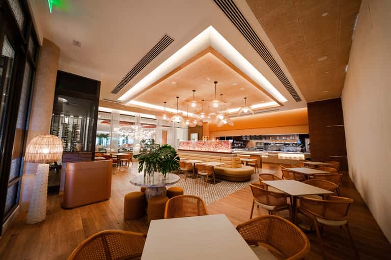 Modern open-concept cafe with orange accents, pendant lighting, and wooden furniture