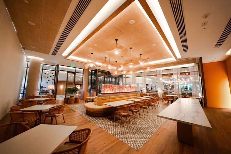 Spacious lobby lounge with orange accents, modern fixtures, and geometric ceiling design