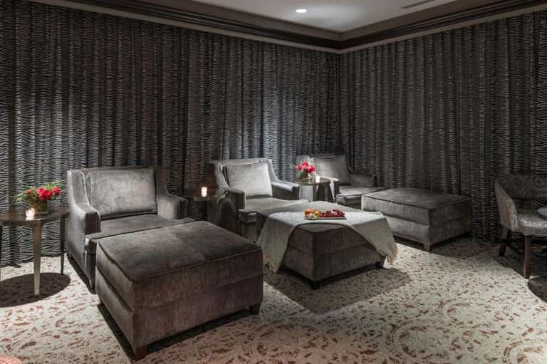 Luxury spa lounge with gray upholstered furniture, textured walls, and soft ambient lighting