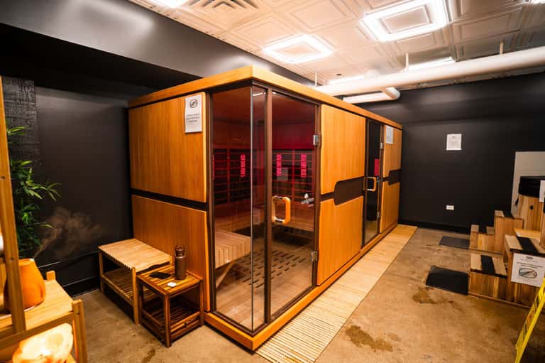 Two wooden infrared saunas with glass doors in spa facility with dark walls and wooden accents