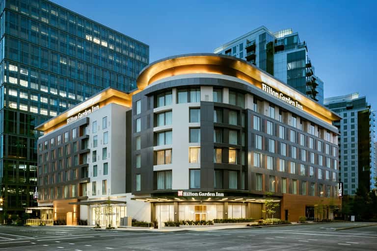 Hilton Garden Inn exterior at dusk with illuminated gold crown signage and modern multi-story architecture