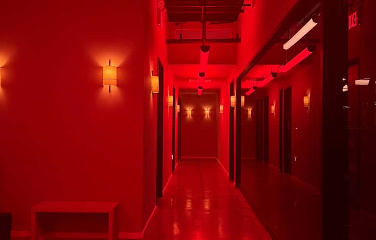 Long hallway with vibrant red walls and warm accent lighting in hotel corridor