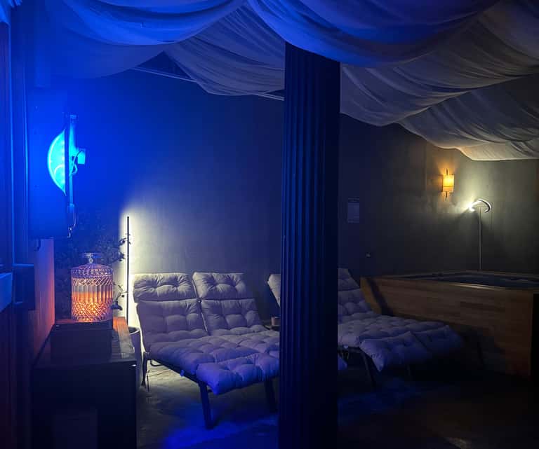 Relaxation lounge with blue neon signage, comfortable seating, ambient lighting, and decorative elements