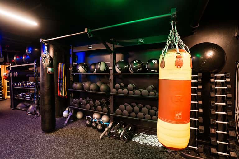 Fitness equipment storage displaying colorful boxing bags, dumbbells, medicine balls, and training gear