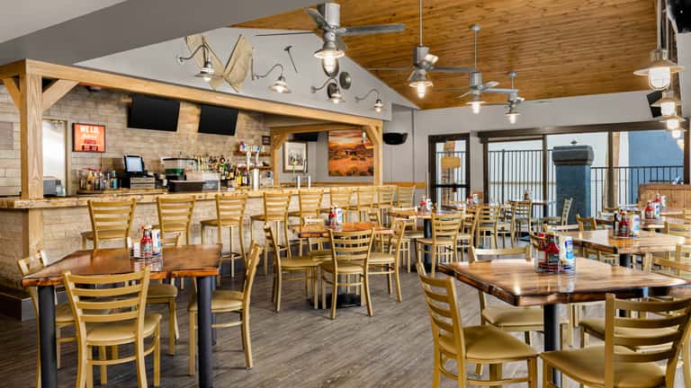 Casual dining restaurant with wooden tables, ladder-back chairs, exposed wood beams and outdoor views