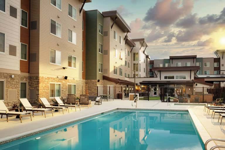 Resort pool surrounded by multi-story residential buildings with stone and siding facades and landscaped grounds