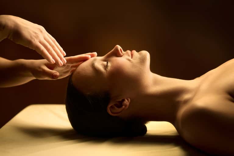 Facial massage treatment with therapist's hands working on client's face and neck