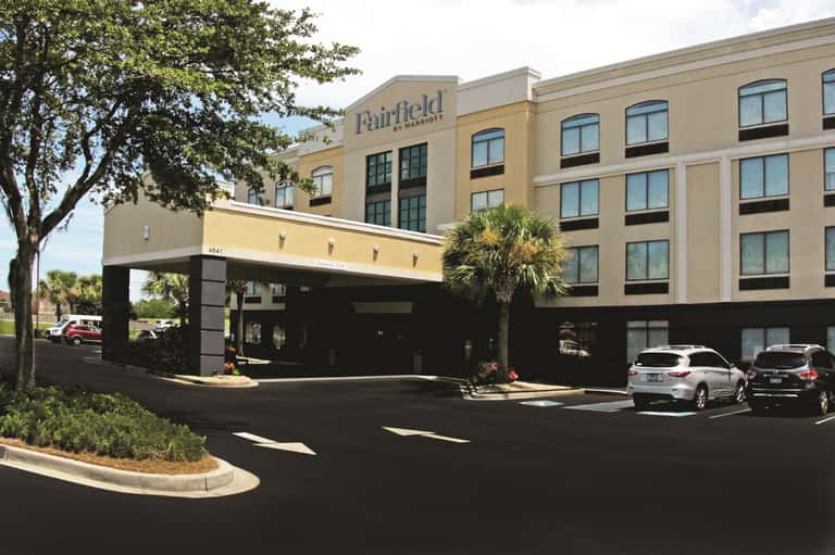 Fairfield by Marriott front entrance with covered driveway, parking area, and palm trees