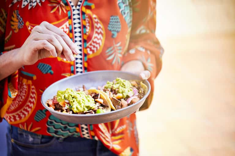Person in colorful patterned clothing holding plate with traditional African food