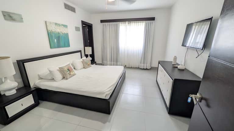 Contemporary bedroom with black and white furnishings, TV, and balcony access