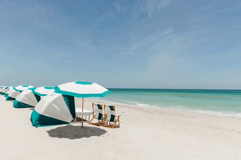 Pristine beach with turquoise umbrellas, lounge chairs, and clear ocean water