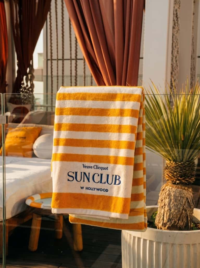 Yellow and white striped beach towel branded 'Veuve Clicquot Sun Club W Hollywood'