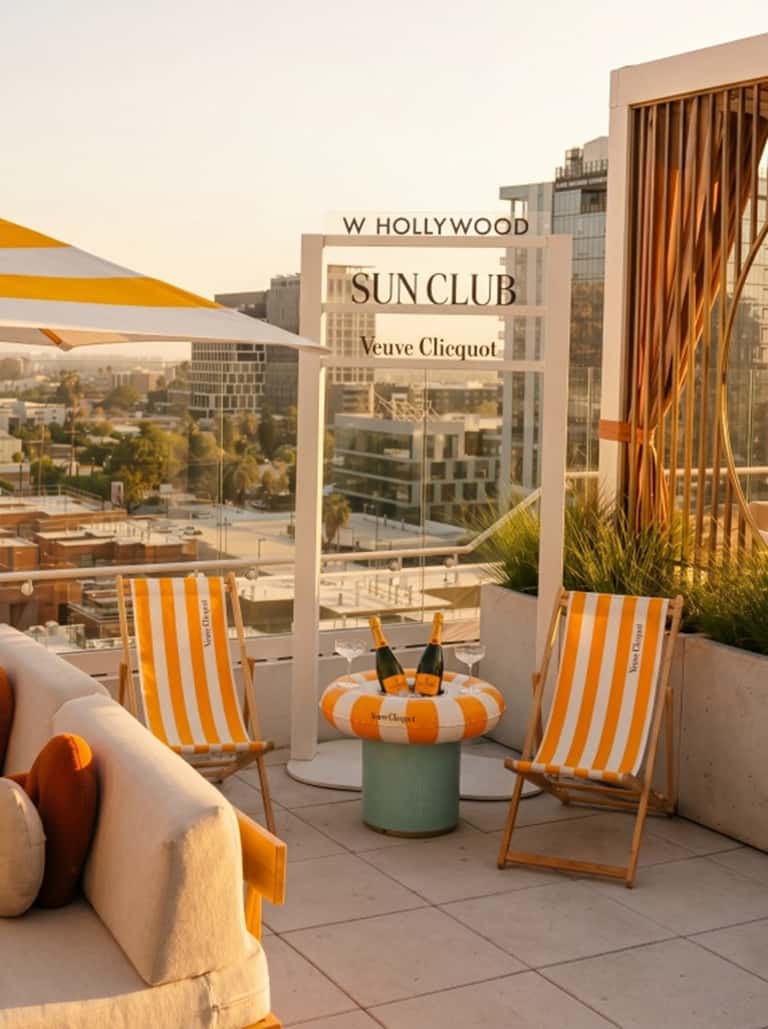 Outdoor lounge area with orange and white striped beach chairs, signage, and city skyline view