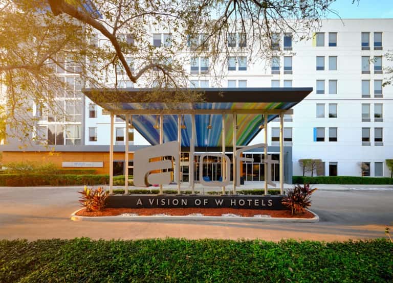 Hotel entrance with 'allo' sign and 'A Vision of W Hotels' tagline beneath modern pavilion structure