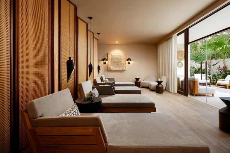 Contemporary spa relaxation lounge with neutral seating, woven room dividers, and garden views
